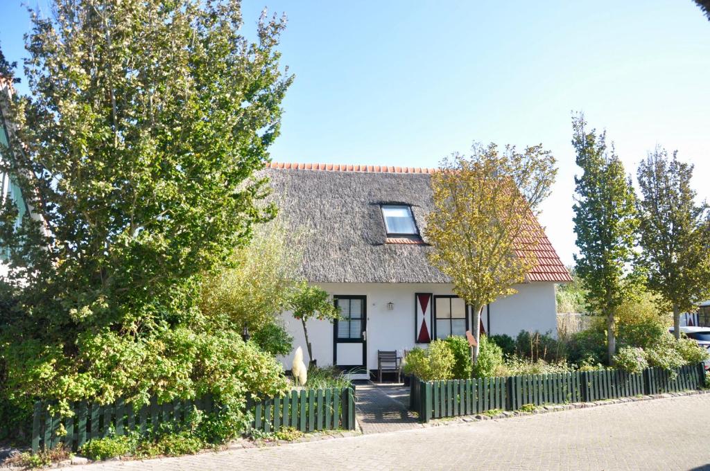 een wit huis met een hek en bomen bij Buitenplaats 90 in Callantsoog