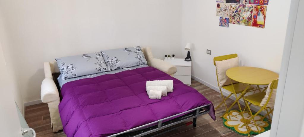 fioletowe łóżko w małym pokoju ze stołem w obiekcie Lago Maggiore Lake Me Home apartment w mieście Sesto Calende