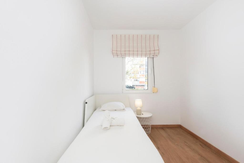 a white bedroom with a bed and a window at Olivais Vintage by Homing in Lisbon