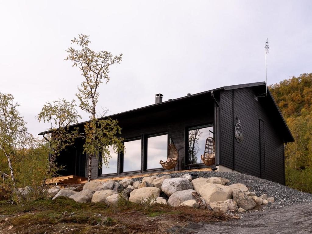 una casa negra con rocas delante de ella en Holiday Home Saanan helmi by Interhome en Kilpisjärvi