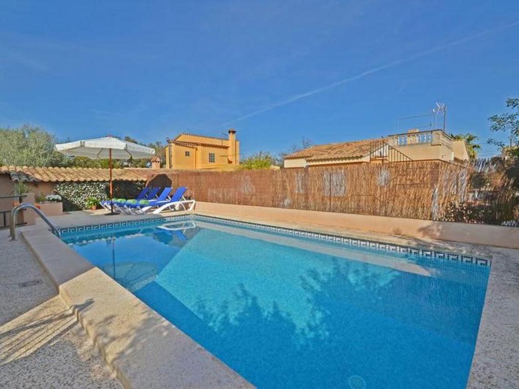 a swimming pool with two blue chairs and a fence at Villa Benestar by Interhome in El Toro