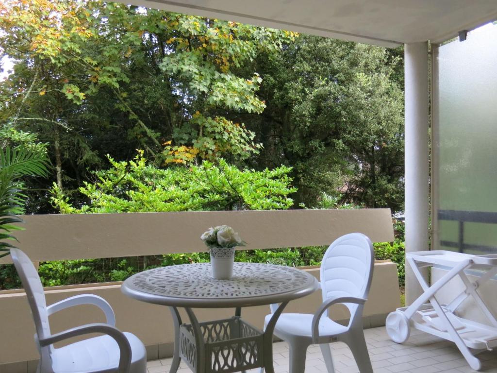 une table et des chaises sur un patio arboré dans l'établissement Apartment La Pomme de Pin by Interhome, à La Baule-les-Pins