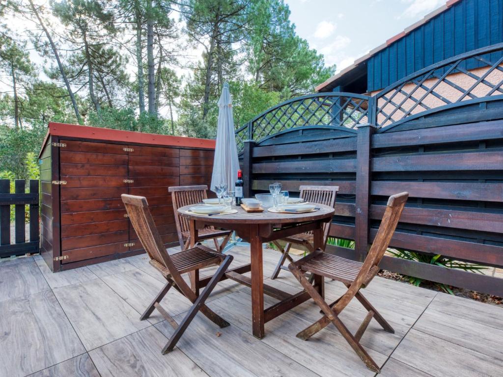 une table en bois avec des chaises et un parasol sur une terrasse dans l'établissement Holiday Home Les Landaises-12 by Interhome, à Lacanau