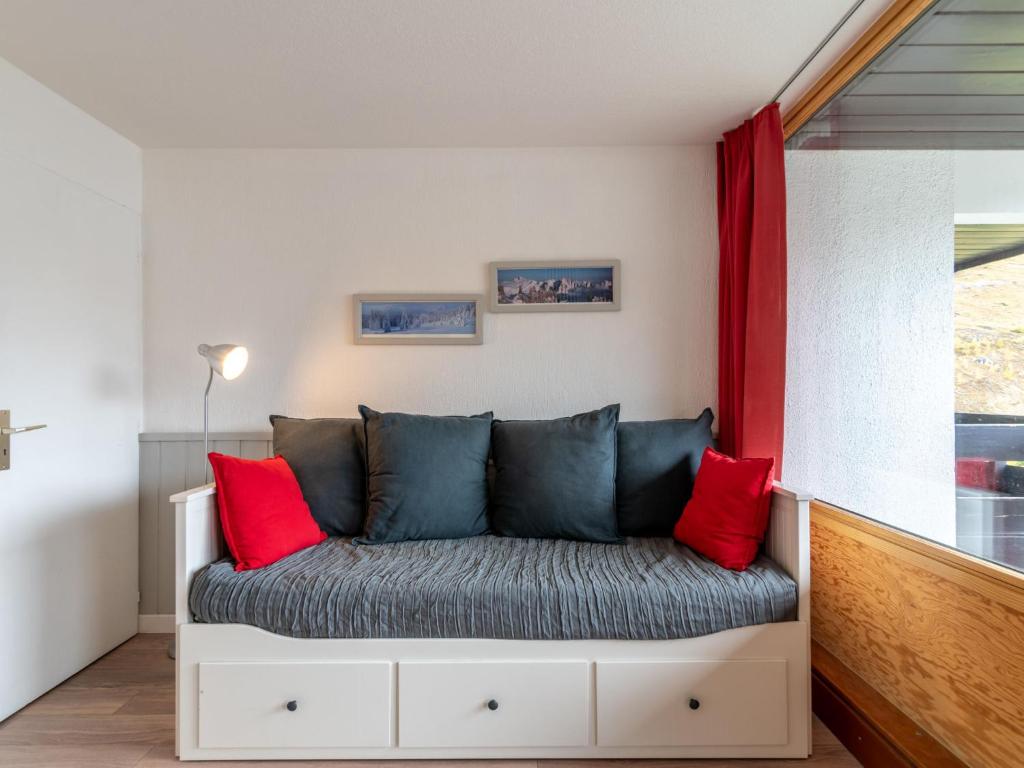a couch with red pillows sitting in a room at Studio Home Club - Lavachet-11 by Interhome in Tignes