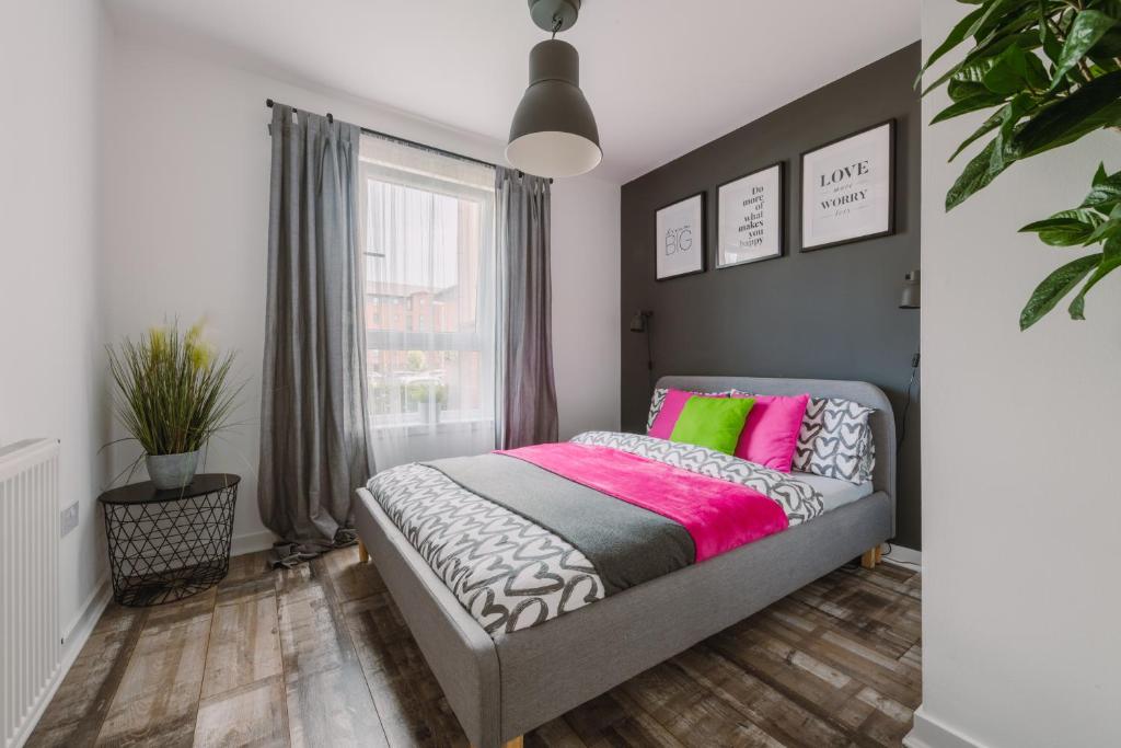 a bedroom with a bed with pink and green pillows at RelaxingSleep Apartments in Glasgow