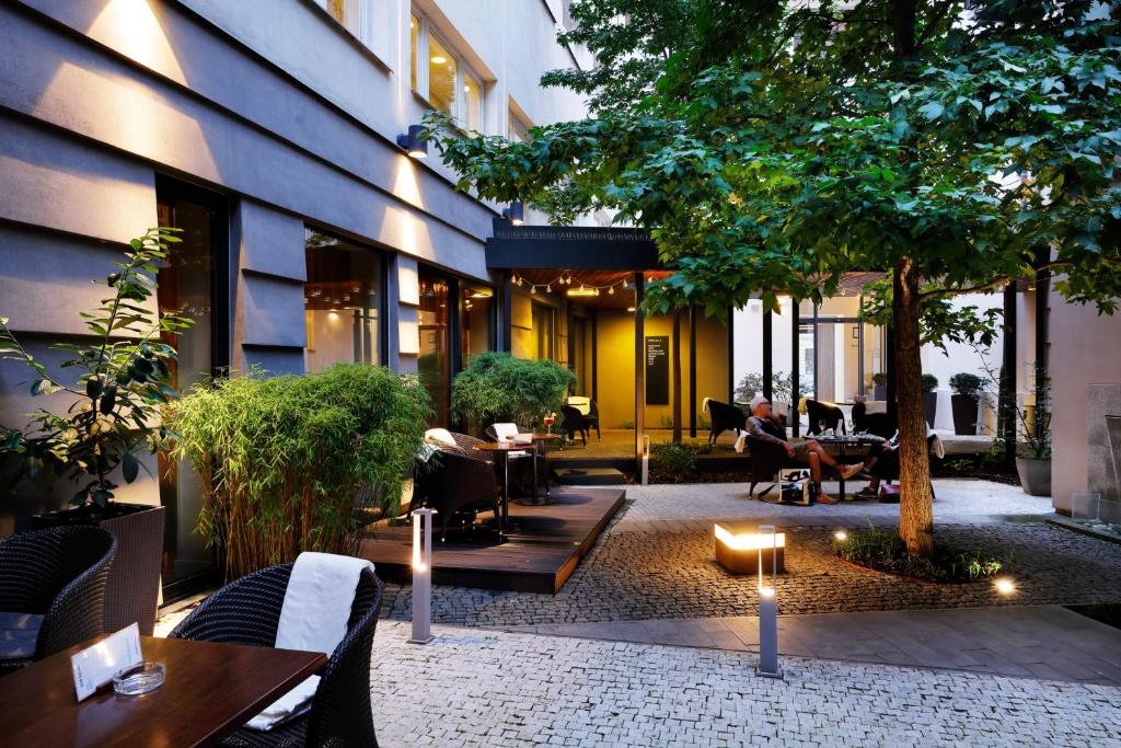 a courtyard of a building with people sitting at tables at Hotel Prokop Square in Prague