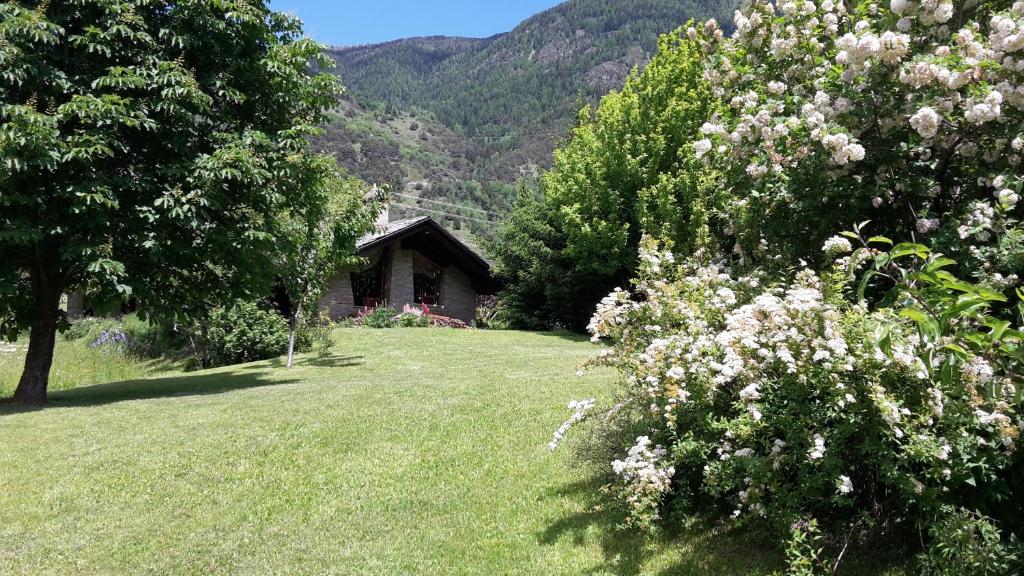 uma casa no meio de um campo com árvores e flores em La Pâquerette em La Salle