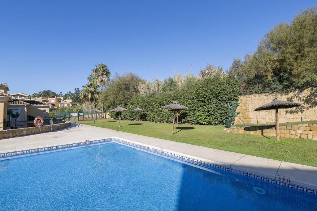 a swimming pool in a yard with umbrellas at Spikes in Guadiaro