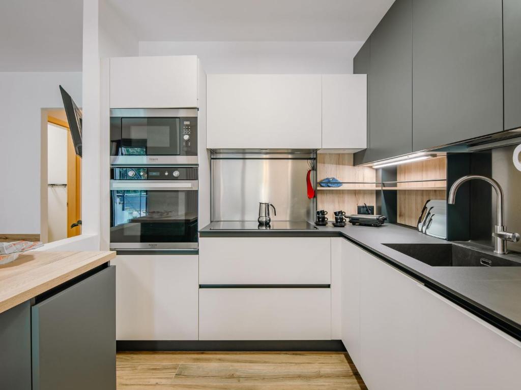 a kitchen with white cabinets and stainless steel appliances at Apartment Enrosadira-9 by Interhome in Alba di Canazei
