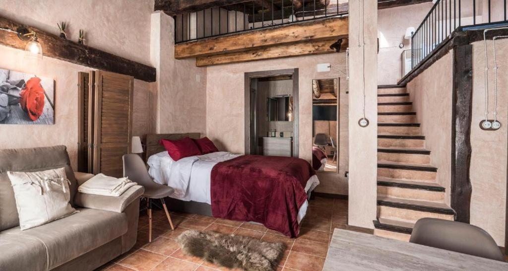 a bedroom with a bed and a staircase and a couch at AbenRazin Turístico Noguera in Albarracín