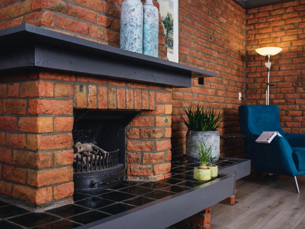 a brick wall with a fireplace with a blue chair at Apartment Delfzijl by Interhome in Delfzijl