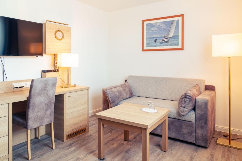 une chambre d'hôtel avec un canapé, une table et un bureau dans l'établissement Hanse Appartement II Warnemünde, à Warnemünde