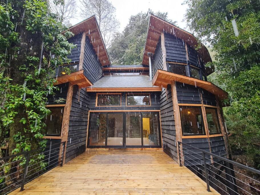 una casa con una pasarela de madera delante de ella en Mágica Casa Enclavada en el Corazón del Bosque, en Reserva Biológica Huilo Huilo