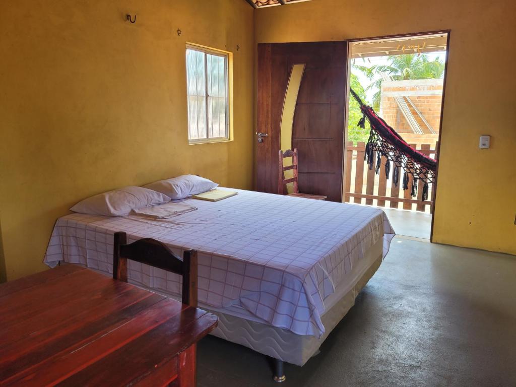 a bedroom with a bed with a table and a window at Vila Coqueiro - Moitas in Amontada