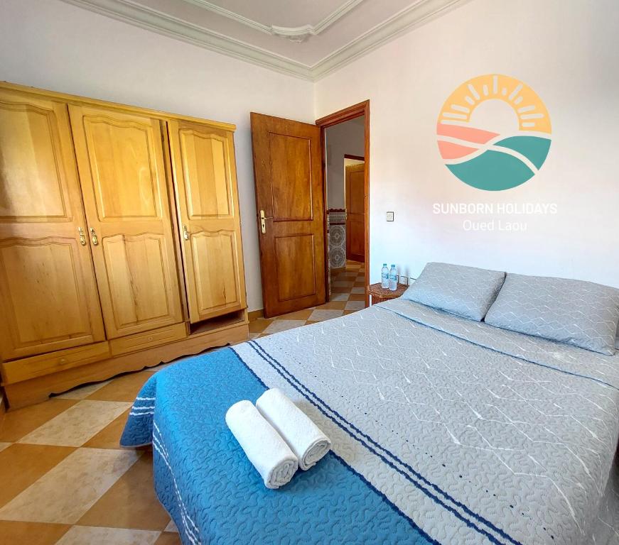 una camera da letto con un letto con lenzuola blu e asciugamani bianchi di Oued Laou Noor - Sunborn Holidays a Oued Laou