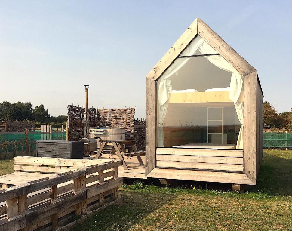 een houten speelhuis met een groot raam bij Lushna 3 Petite at Lee Wick Farm Cottages & Glamping in Clacton-on-Sea