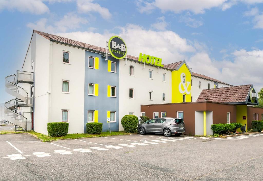 a hotel with a car parked in a parking lot at B&B HOTEL Nancy Laxou Zenith in Nancy