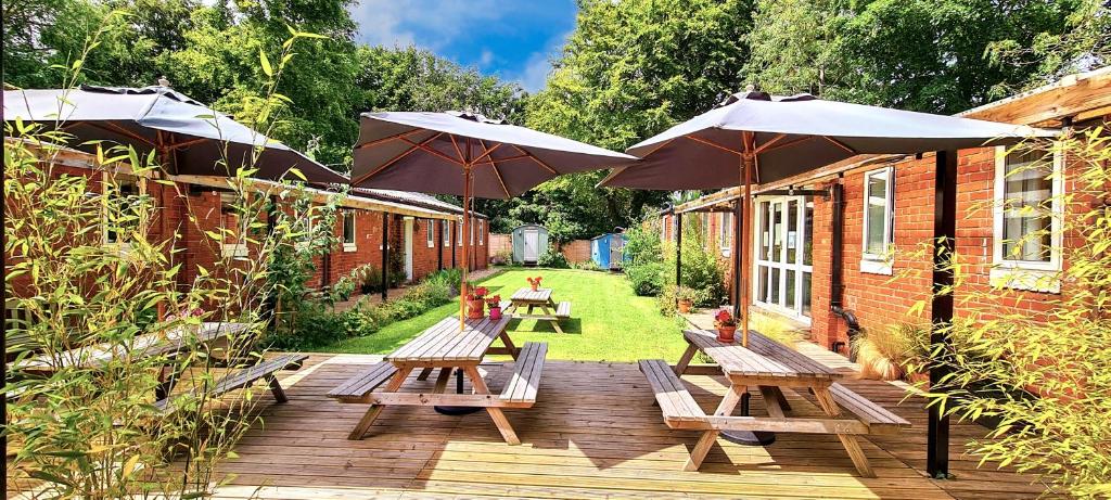 una terrazza in legno con tavoli da picnic e ombrelloni di Wooler Youth Hostel and Shepherds Huts a Wooler