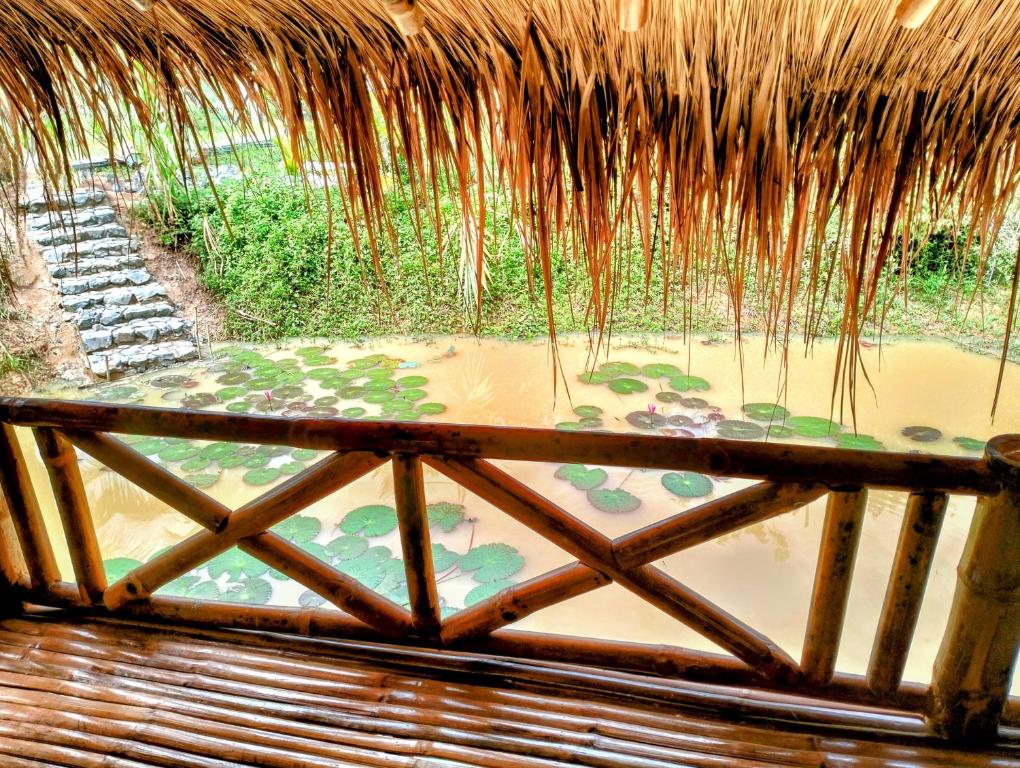 a thatch roofed patio with a pool of water at Banteay Srey Women's Only Traditional Spa and Homestay in Kampot