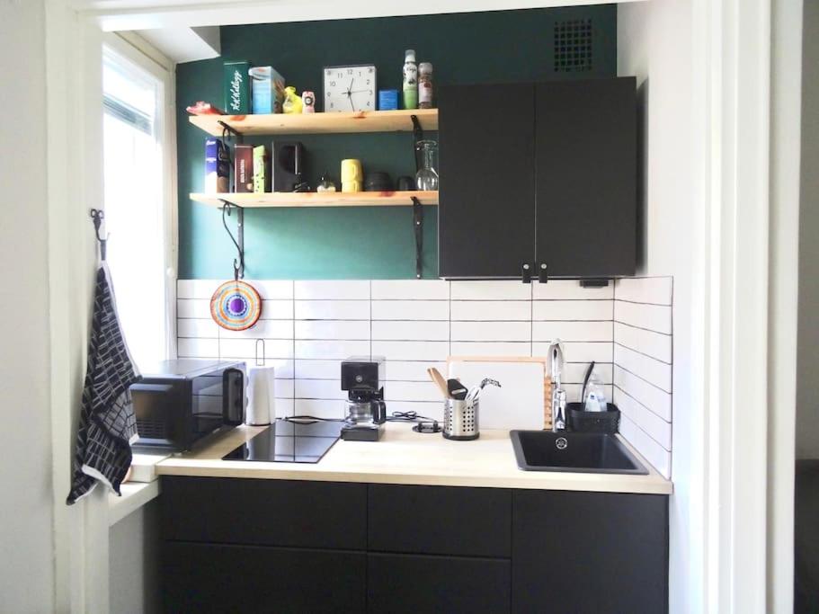 a kitchen with black cabinets and a sink at Studio in the center area with free street parking in Vaasa