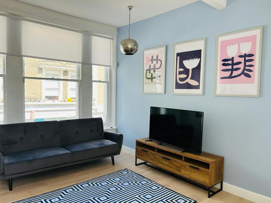 a living room with a couch and a flat screen tv at Elegant 1st Floor 1BR Belsize Park Apartment in London