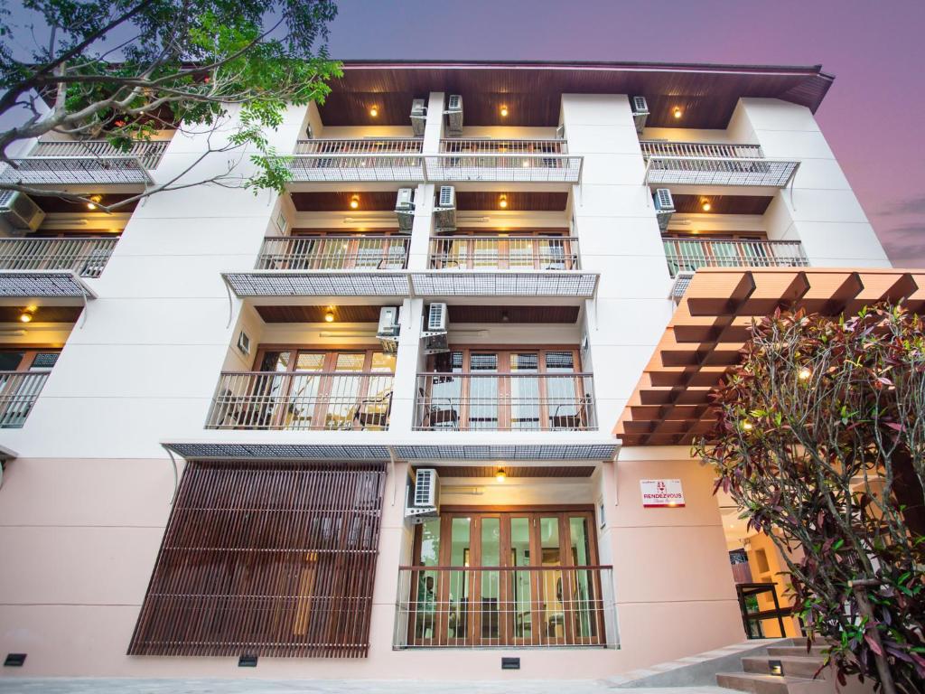 a tall white building with balconies and trees at Rendezvous Classic House in Chiang Mai