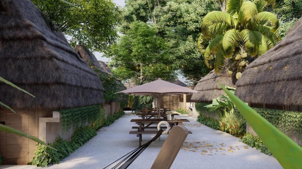 a patio with tables and an umbrella in a resort at Maya Cabaña Hostel in Bacalar