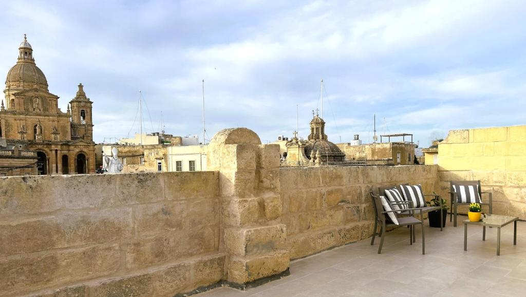 uma varanda com 2 cadeiras e uma mesa na parede em The Siggiewi Suites em Siġġiewi