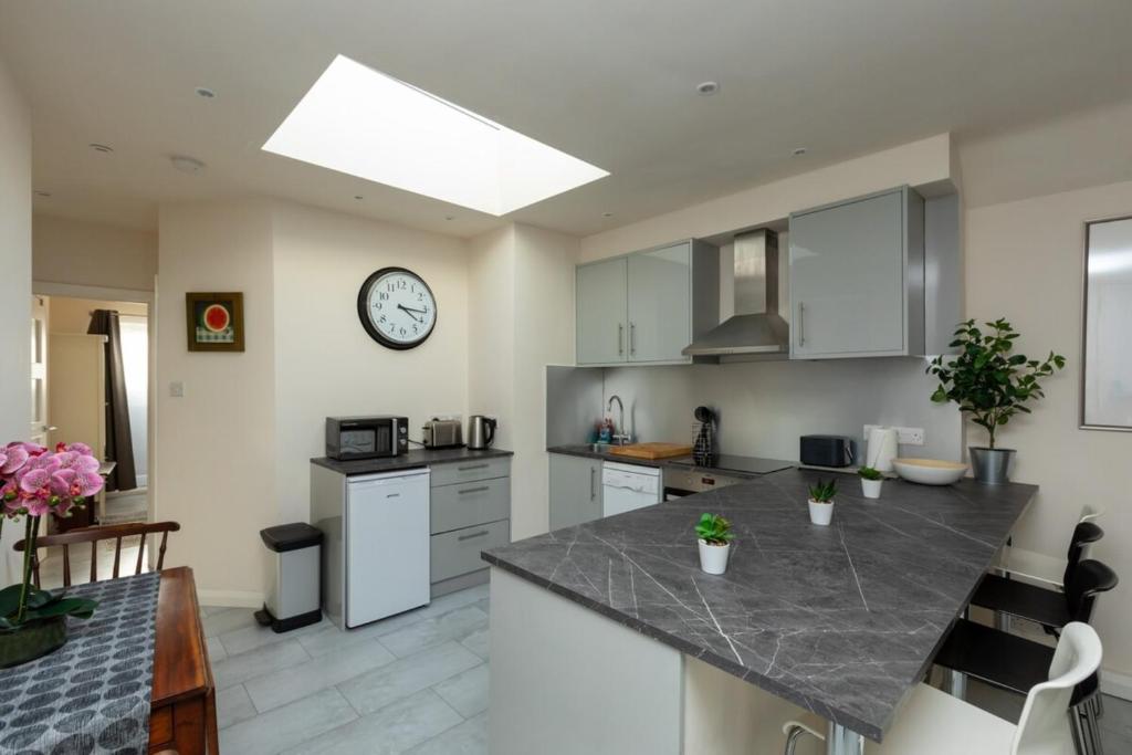 a kitchen with a counter and a clock on the wall at Bright & Contemporary 1bedroom Annexe - Herne Hill! in London