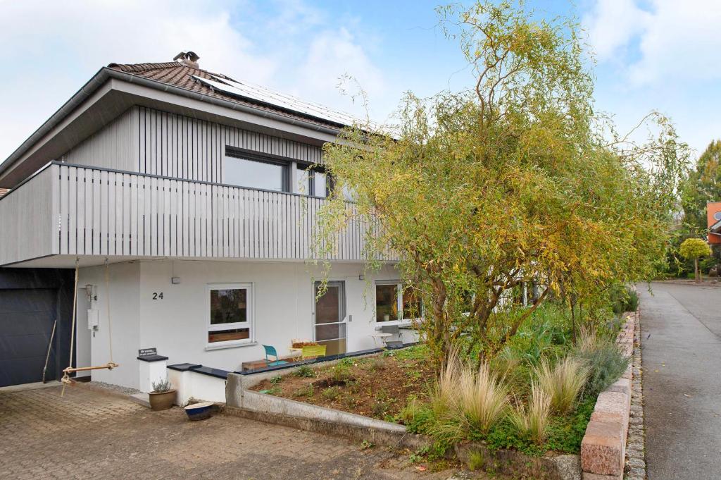 a white house with a tree in front of it at Apartment Dreiländer Blick 