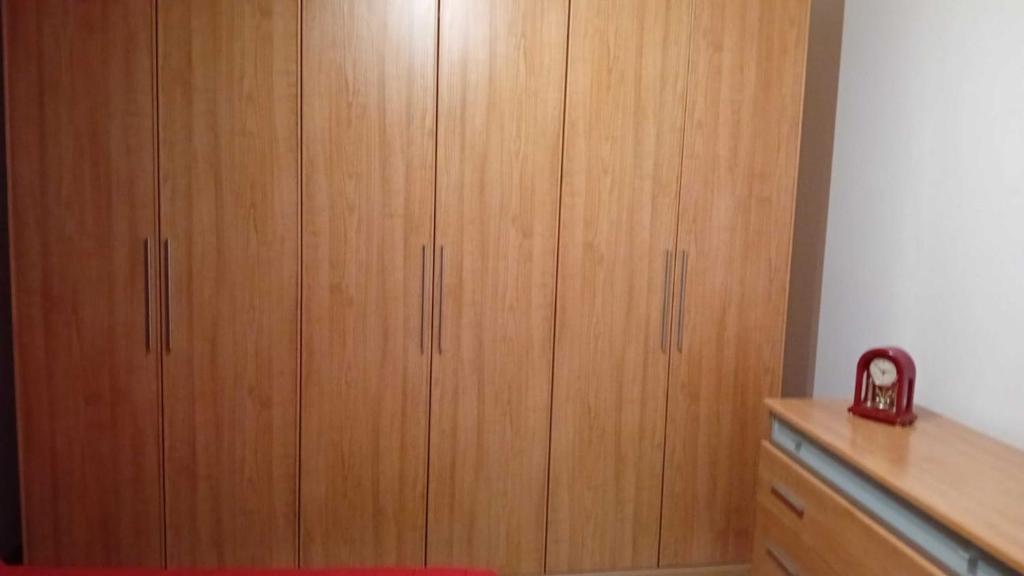 1 dormitorio con armarios de madera y 1 cama roja en La casetta di Ele, en Sassari