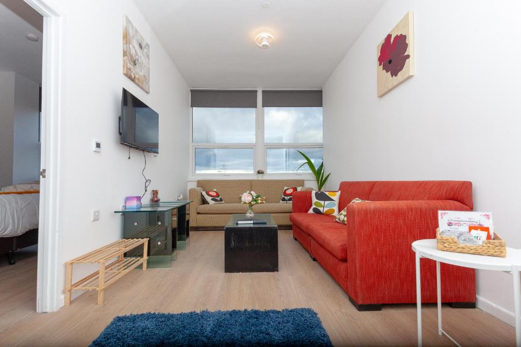 a living room with a red couch and a tv at One bedroom serviced apartment Smethwick flat 310 in Birmingham