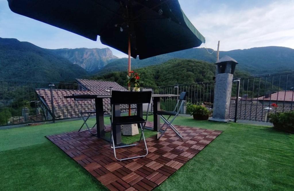 a table and chairs under an umbrella on a lawn at Casa Vacanze Al Colletto - Con terrazza panoramica in centro storico in Vagli di Sotto