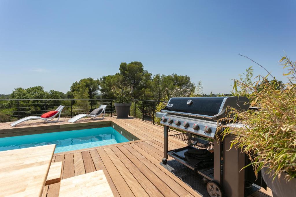een grill op een terras naast een zwembad bij Villa Le Golf St Thomas 19 pers in Béziers