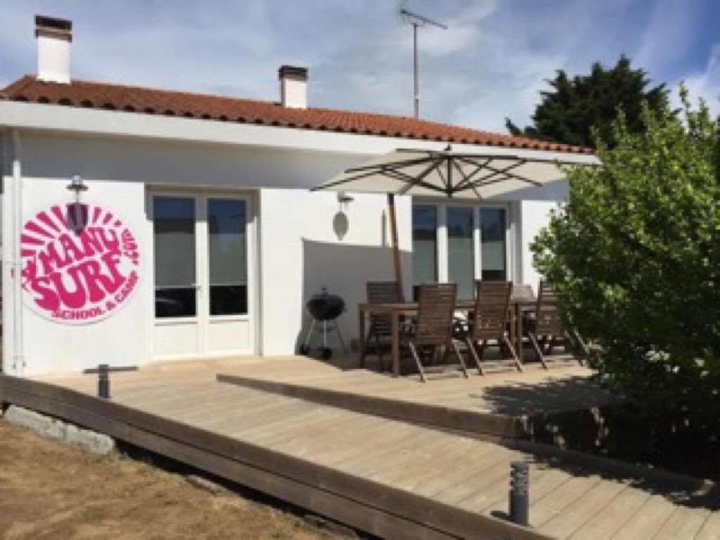 a white building with chairs and an umbrella at Maison avec Jardin près des Plages in Le Bernard