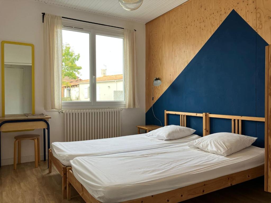 a bedroom with a large bed with a blue headboard at Maison avec Jardin près des Plages in Le Bernard