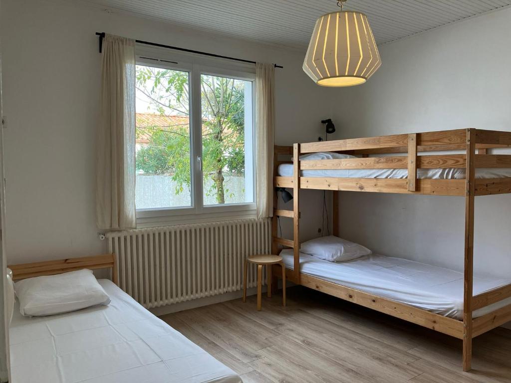 a bedroom with two bunk beds and a window at Maison avec Jardin près des Plages in Le Bernard