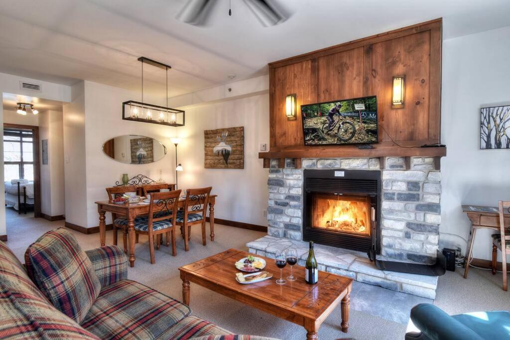 a living room with a fireplace and a table at Tremblant-Les-Eaux C2 in Mont-Tremblant