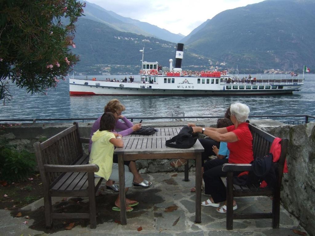 a group of people sitting at a table with a boat in the water at Appartamento San Vito in Cremia