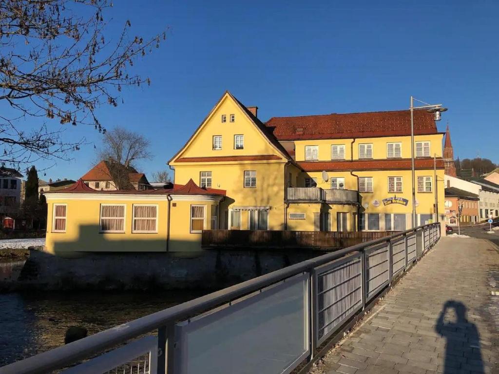 a shadow of a person standing in front of a yellow building at Gästezimmer zur Brücke in Zwiesel