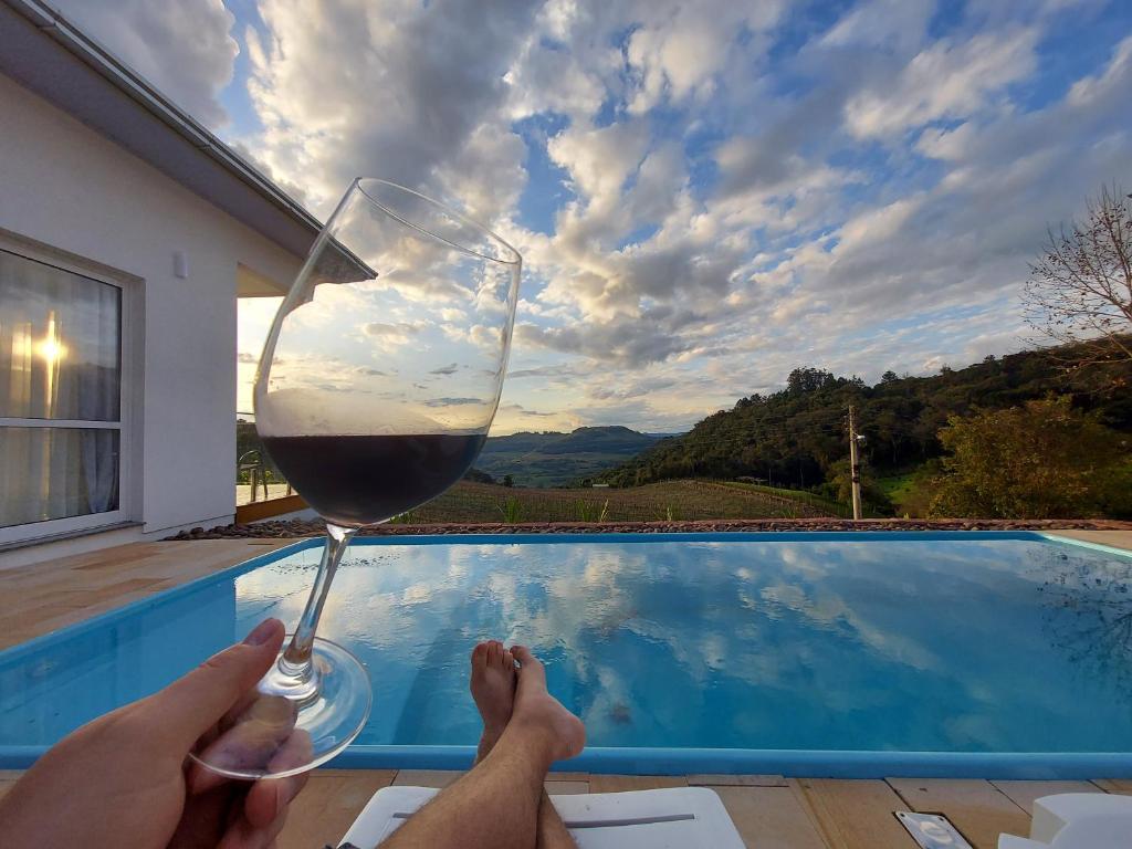 una persona sosteniendo una copa de vino junto a una piscina en Pousada San Doná en Bento Gonçalves