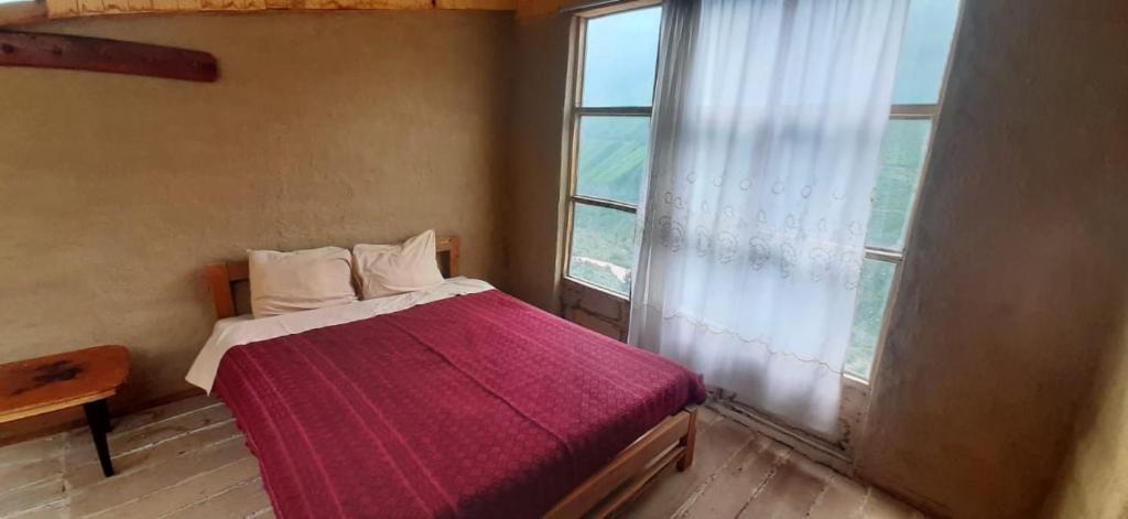 a bedroom with a bed with a large window at Vrindavan Perú Jardín Ecológico in Matucana