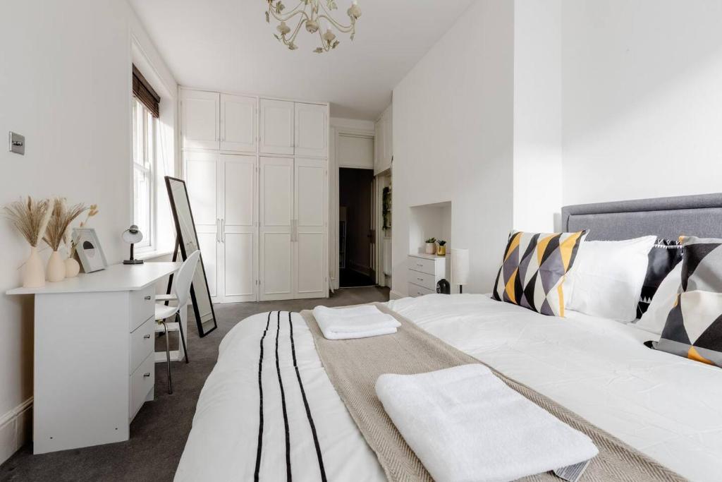 a white bedroom with a large bed and a desk at Spacious Apt In Central London in London