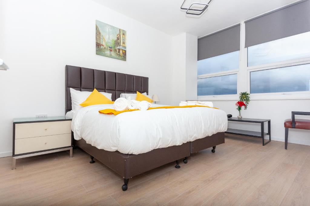 a bedroom with a large bed with yellow pillows at One bedroom serviced apartment Smethwick F312 in Birmingham
