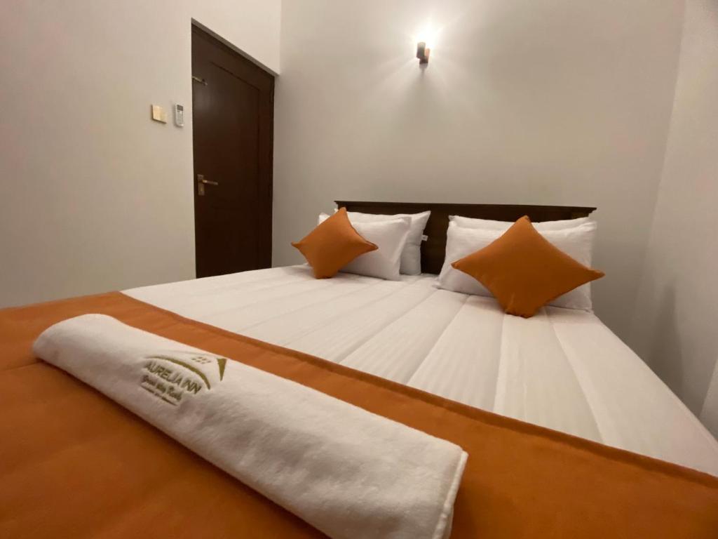 a bedroom with a large bed with orange and white pillows at Aurelia inn in Kandy