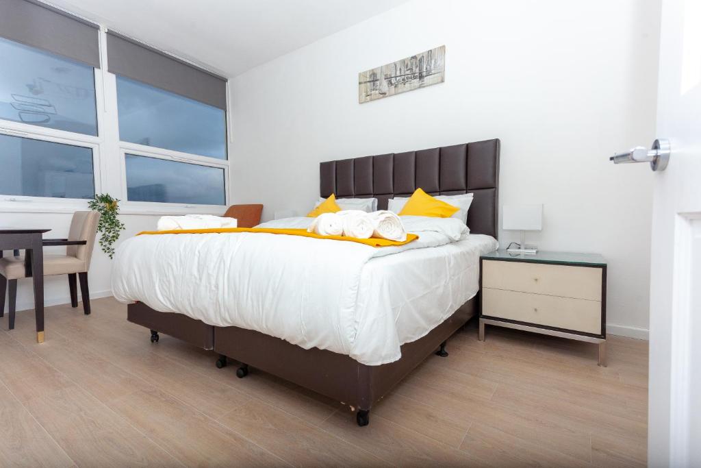 um quarto com uma cama grande e almofadas amarelas em One bedroom serviced apartment Smethwick Flat 314 em Birmingham