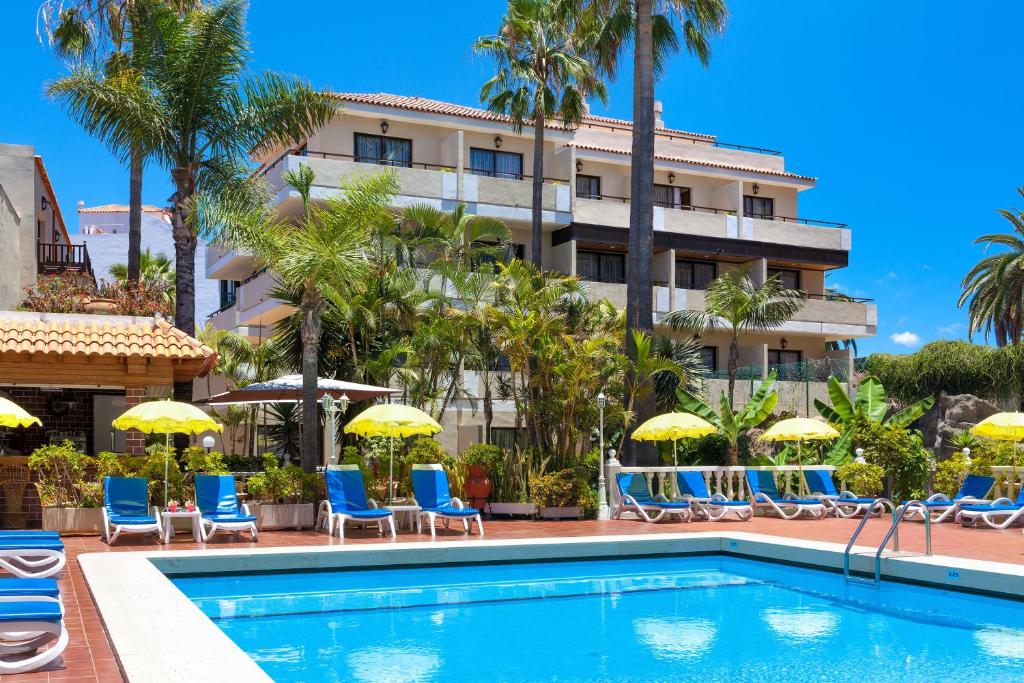 a hotel with a swimming pool with chairs and umbrellas at Hotel Don Manolito in Puerto de la Cruz