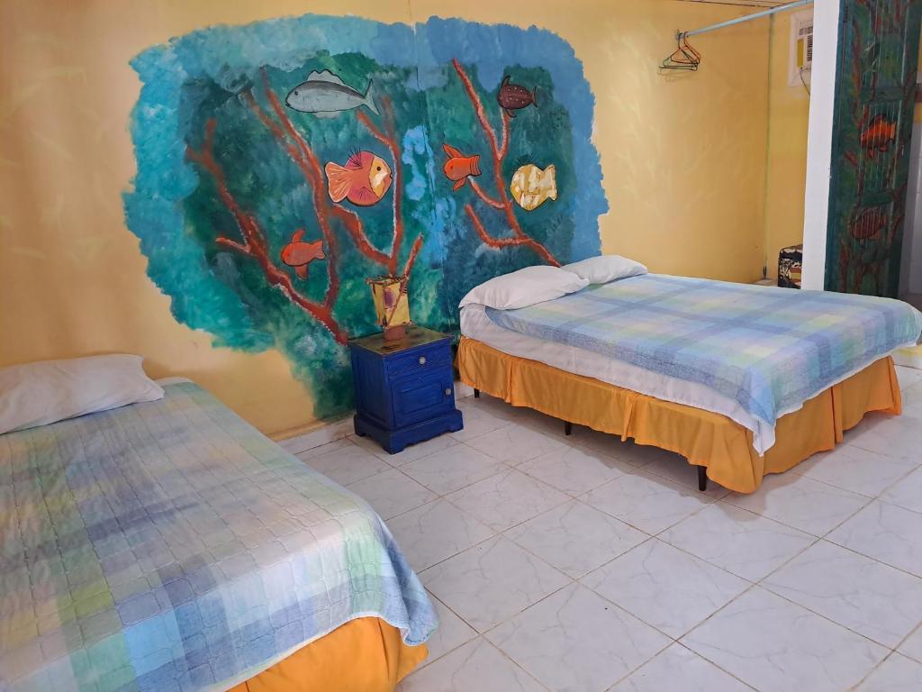 Cette chambre comprend deux lits et un tableau mural. dans l'établissement Villa Bella, à Portobelo