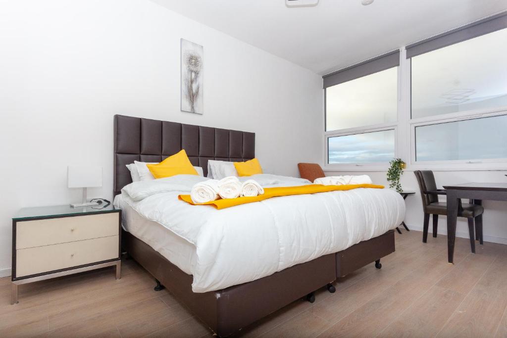 um quarto com uma cama grande e almofadas amarelas em One Bedroom apartment Serviced apartment Smethwick flat 315 em Birmingham