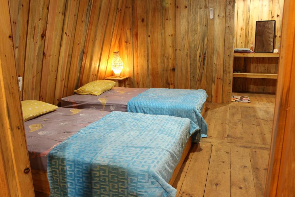 two beds in a room with wooden walls at Sultan Resort Syariah in Payakumbuh